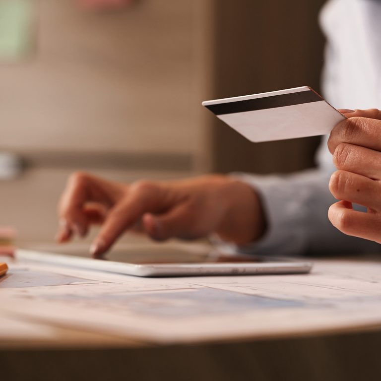 Close up of woman holding credit card and e-banking at her offic